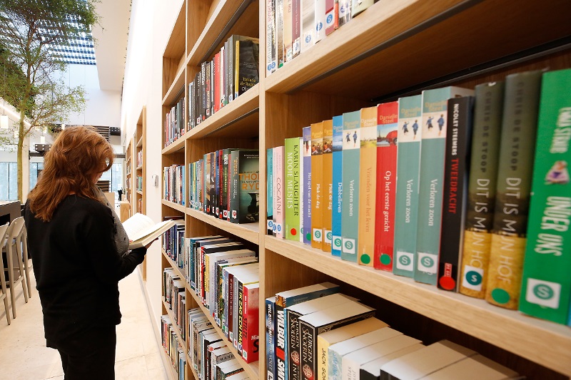 Een mevrouw staat voor een boekenrek